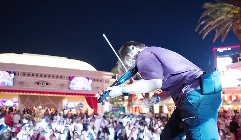 Violinist performing for a crowd at an outdoor Las Vegas event at night